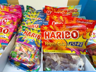 Venedik, İtalya - 14 Şubat 2026: Bir kutuda çeşitli Haribo şekerleme paketleri, renkli tasarımlar ve Happy Cola ve Frizzi gibi farklı tatlar sergileniyor