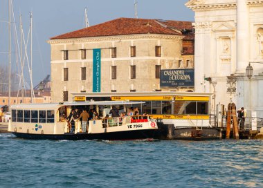 Venedik, İtalya - 07 Şubat 2026: Vaporetto su otobüsü Venedik 'teki Büyük Kanal' da geziyor ve yakınlarındaki tarihi mimari ve tekneleri gösteriyor.