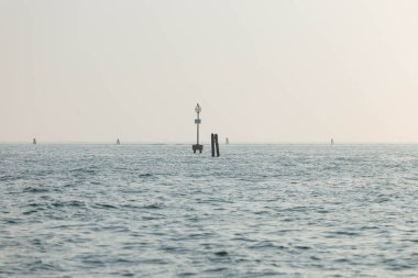 Gün batımında ufuk ve seyir şamandıralarıyla sakin bir okyanus manzarası.