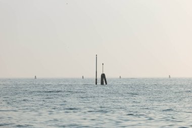 Sakin okyanus manzarası bulutlu gökyüzü altında uzak sütunlar.