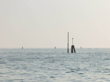 Açık gökyüzü altında navigasyon işaretleri olan sakin bir okyanus manzarası.