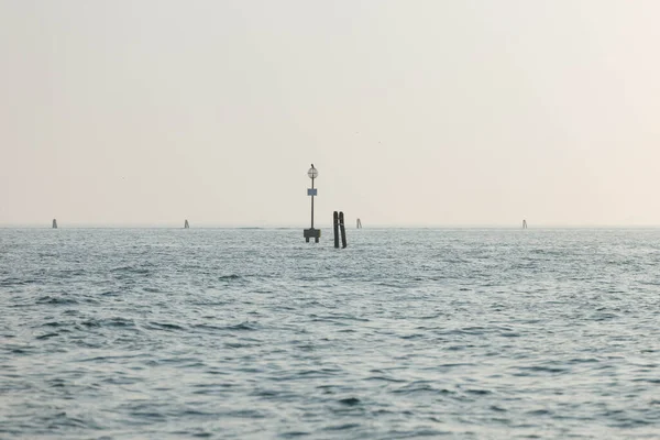 Gün batımında ufuk ve seyir şamandıralarıyla sakin bir okyanus manzarası.