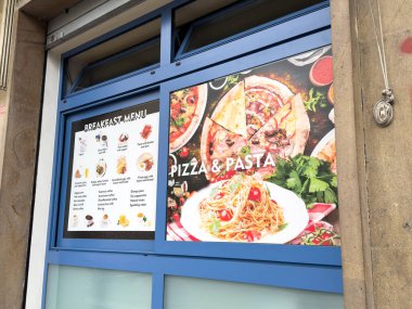 Venedik, İtalya - 10 Şubat 2026: Restoran vitrininde canlı bir pizza ve makarna menüsünün yanında çeşitli gıda öğeleri sergileniyor