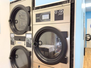 Venedik, İtalya - 10 Şubat 2026: Dijital kontrollü ve geniş pencereli bir çamaşırhanede modern tasarım ve işlevsellik gösteren endüstriyel çamaşır makineleri