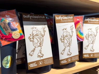 Villach, Avusturya - 29 Ocak 2026: Ahşap bir rafta renkli bufnissima ürün ambalajı, oyuncu çizimler ve çocuk aksesuarları için canlı tasarımlar sergileniyor