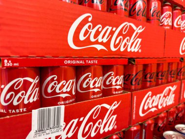 Villach, Avusturya - 29 Ocak 2026: Logo ve orijinal tat etiketi perakende ortamında görülebilen kırmızı paketlerde istiflenmiş Coca-Cola kutuları