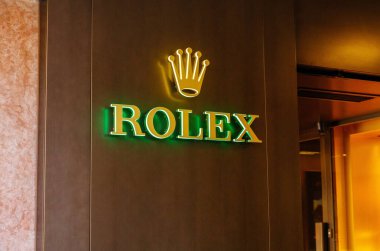 Cortina D Ampezzo, İtalya - 07 Mart 2026: Modern tasarım elementlerinin yer aldığı lüks bir perakende mağazasının ahşap duvarında aydınlatılmış Rolex logosu