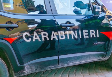 Cortina D Ampezzo, İtalya - 07 Mart 2026: Bir kaldırım taşı caddesinde parkedilmiş görünür markalı jandarma polis arabası, kentsel mimari ve yansımaları gözler önüne seriyor