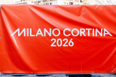 Cortina D Ampezzo, İtalya - 07 Mart 2026: Milano Cortina 2026 pankartı halka açık bir alanda görülüyor ve etkinliğin markasını parlak renklerle gösteriyor