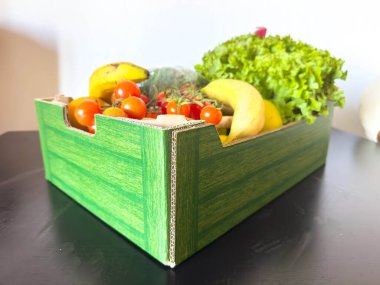 Siyah yüzeydeki çevre dostu karton kutuda taze ürün çeşitliliği.