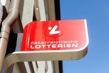 Villach, Avusturya - Mart 06, 2026: Osterreichische Lotterien tabelası açık mavi gökyüzü olan bir binaya asılarak, markanın logosu ve görünürlüğü vurgulandı