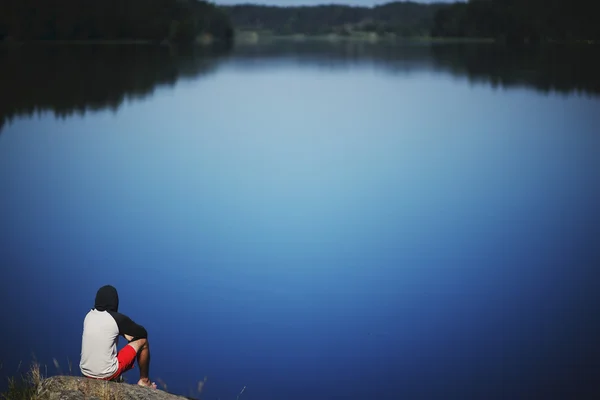 Joven sentado en la piedra disfrutando de un momento de paz — Foto de Stock