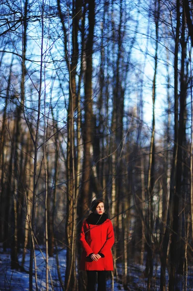 Wczesną wiosną portret ładny atrakcyjny poważne młoda dziewczyna z ciemne włosy ciepła apaszka i czerwona kurtka patrząc na kamery i stojąc na dziki Las naturalny kontekst. Odkryty — Zdjęcie stockowe