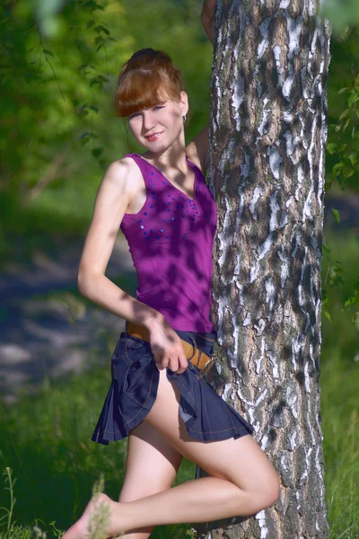 Beautiful young lady in purple blouse and denim skirt posing out