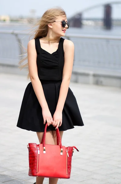 年轻的女士，在黑色的裙子、 无袖衬衫和时尚袋岗位 — 图库照片
