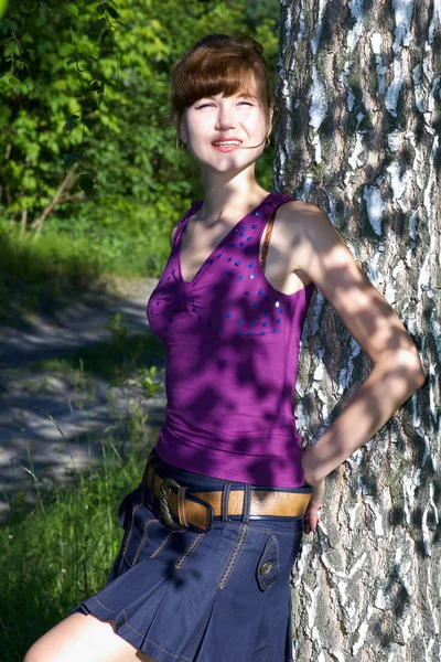 Krásná mladá dáma v fialová halenka a džínové sukně pózuje venku — Stock fotografie