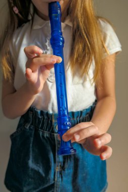 Yeteneğiyle oynayan küçük kız soprano kaydedici, mavi flüt. Kapatın. Yüksek kalite fotoğraf