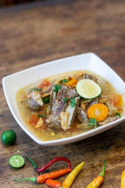 Geleneksel Endonezya biftek çorbası veya ahşap masada sebze, limon ve kırmızı biberle servis edilen çorba.