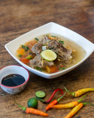 Geleneksel Endonezya et çorbası, berrak et suyu, sebze ve limonlu garnitür.