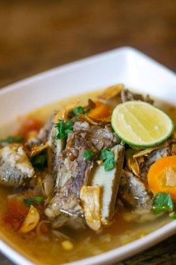 Geleneksel Endonezya et çorbası, berrak et suyu, sebze ve limonlu garnitür.