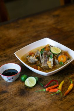 Geleneksel Endonezya biftek çorbası veya ahşap masada sebze, limon ve kırmızı biberle servis edilen çorba.