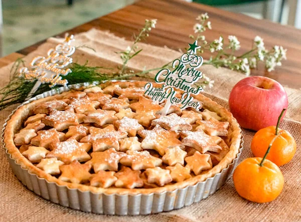 Yıldız şeklindeki kabuk ve pudra şekerle süslenmiş lezzetli ev yapımı Noel pastası taze meyve ve kırsal festival elementleriyle servis ediliyor. Tatil, kutlama ve yemek konsepti için ideal..