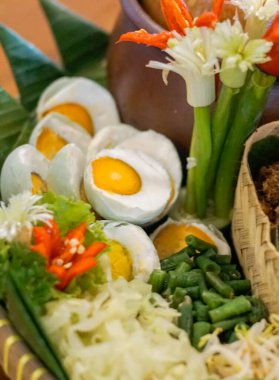 Geleneksel tuzlu yumurta, sebze garnitürlü ve bambu servisli acılı çiçek. Doğal malzemeli ve etnik sunumlu otantik Endonezya yemekleri