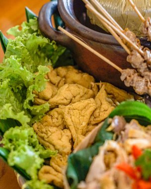 Otantik Endonezya usulü kızarmış tofunun taze marullu yakın plan fotoğrafı. Kırsal gıda sunumu mutfak, restoran ve editoryal tasarım için ideal.