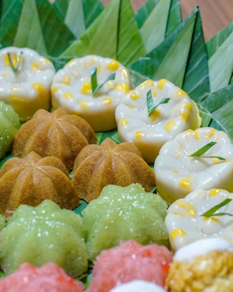 Endonezya geleneksel tatlılarının muz yaprakları üzerinde düzgünce sıralanmış yakın çekim makro fotoğrafı. Pirinç unu ve hindistan cevizinden yapılmış otantik Asya tatlı çeşitleri, mutfak tasarımı ve editoryal içerik için ideal..