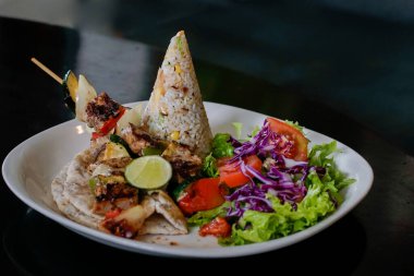 Pirinç konisi, domates, marul, lahana ve taze salata ile ızgara et şişleri yakından görülebilir. Sağlıklı yemek temaları, restoran menüleri, diyet konseptleri, tarifler ve mutfak pazarlama görselleri için ideal.