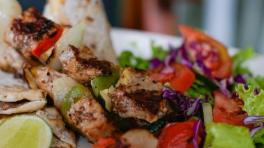 Taze salata, domates, marul, mor lahana ve limonla servis edilen ızgara et şişleri. Restoranlar, menüler, sağlıklı beslenme, bloglar ve mutfak içeriği için ideal.