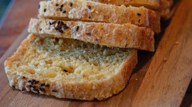 Tahta bir tahtanın üzerine yerleştirilmiş dilimlenmiş zanaatkar ekmeğinden sıcak makro shot. Yemek tarifleri, pastane reklamları, yemek blogları ve mutfak görselleri için harika.