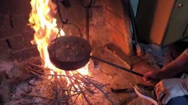 Kırsal bir mutfakta, kırsal bir kamp ateşinde kestane kızartan bir kadının videosu.