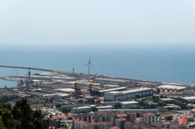 Viana do Castelo 'nun sanayi ve liman bölgesinin panoramik manzarası, tersaneleri, vinçleri ve rüzgâr türbinlerini ön plana çıkarıyor.