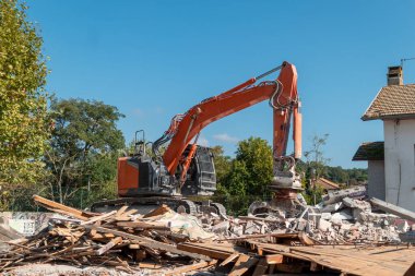 Yıkımda kullanılan kepçe yükleyici, yeni bir binanın inşası için eski bir altyapı üzerinde çalışıyor.