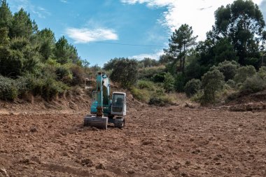 Doğanın ortasında yeni tarımsal projeler için toprak hazırlayan bir kazıcı ile manzara dönüşümü