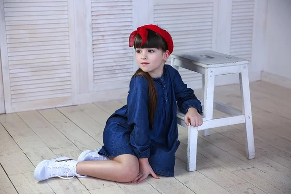 Дівчина в блакитній сукні і червоний лук, сидить на білому стільці — стокове фото