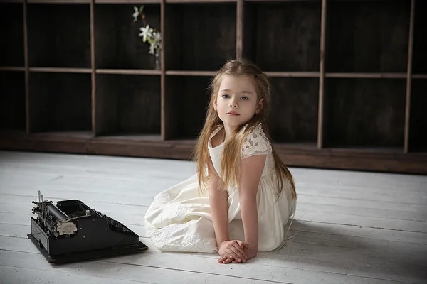 Katta önünde eski daktilo oturan beyaz elbiseli kız — Stok fotoğraf