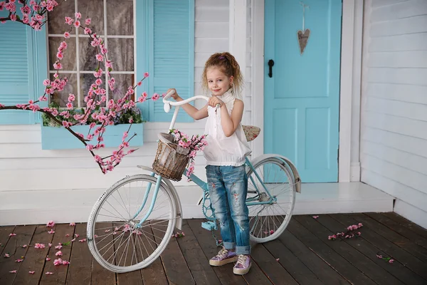 Sakura ve bir bisiklet ile bir ev yakınındaki küçük kız — Stok fotoğraf