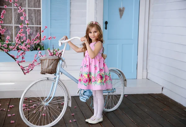 Sakura ve bir bisiklet ile bir ev yakınındaki küçük kız — Stok fotoğraf