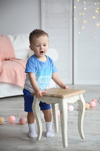 Sevimli küçük çocuk bir şekilde dekore edilmiş oda bir sandalyede yakınındaki ayakta