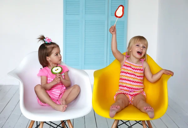 küçük kızlar sandalyede oturma ve yemek çubukları şeker
