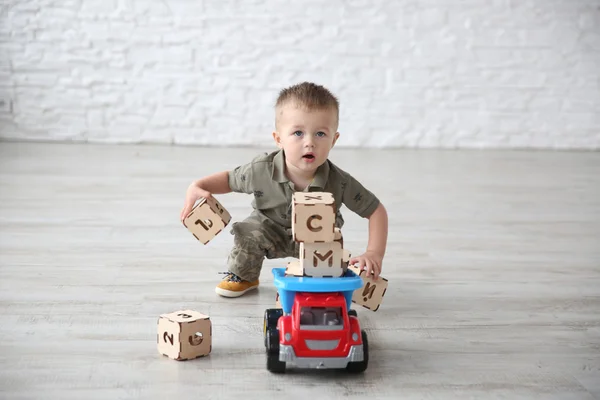 Oyuncak arabalar ve ahşap mektup oyuncak blok ile odada oynayan çocuk çocuk
