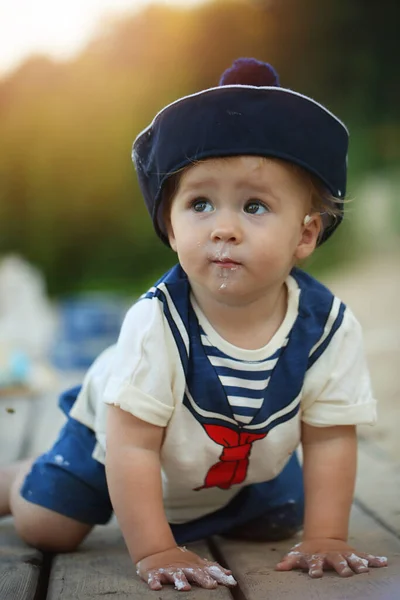 Dziecko w mundurze marynarza siedzi na molo — Zdjęcie stockowe