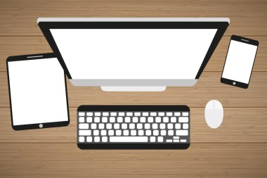 Ahşap bir masa işyerinde. Monitör, klavye, bilgisayar faresi, tablet ve akıllı telefon