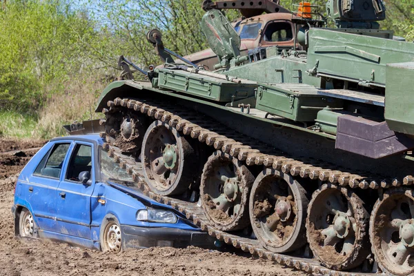 Військовий танк подрібнює синій автомобіль — стокове фото