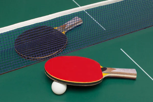 Twee tafel tennis racket rood en zwart op een groene tafel — Stockfoto