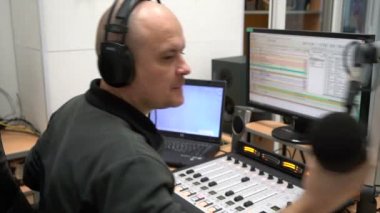 Adam radyo DJ 'i bir bilgisayar radyo istasyonunun uzaktan ekolayzırında oturur ve mikrofona konuşur.