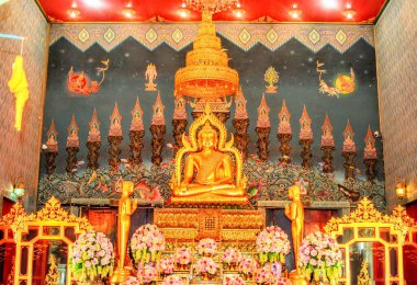 16 Temmuz 2015. Luang Por Phet 'in altın Buda heykeli Maravichai duruşu Wat Tha Luang, Phichit, Tayland' da, geleneksel duvar resimleri ve çiçeklerle.