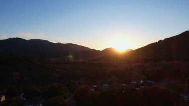 Gün batımında dağlardaki bir karavan kampının insansız hava aracı görüntüleri.
